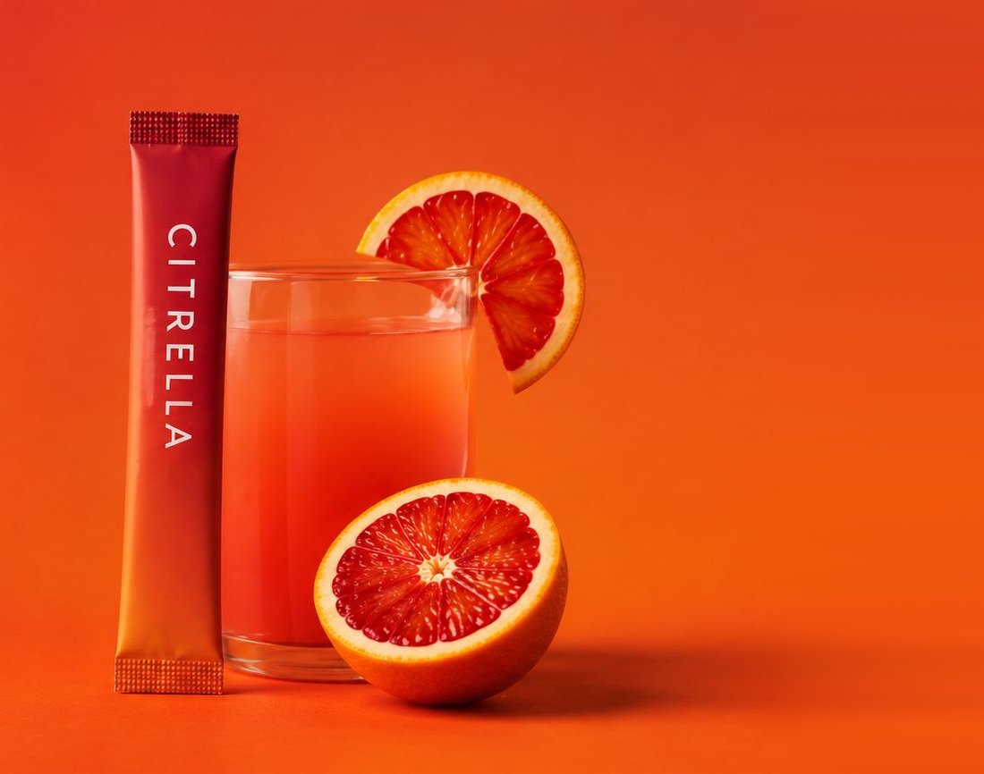 Citrella slim stick naast een glas bloedsinaasappeldrank en twee halve sinaasappels