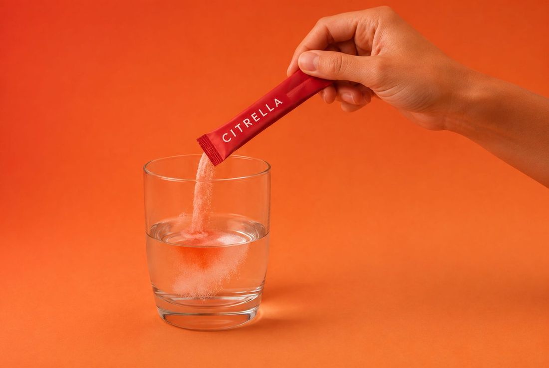 Hand die het poeder van een Citrella slim stick in een glas water schenkt